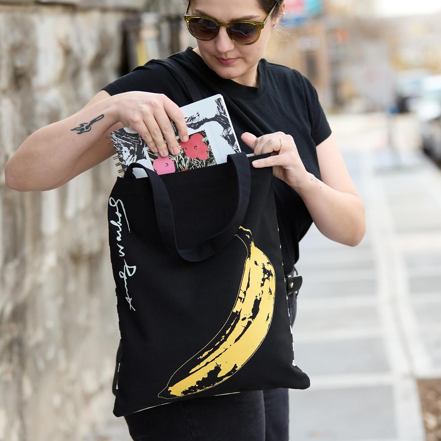 Czarna torba podręczna Warhol Banana z żółtym nadrukiem banana noszona przez kobietę na spacerze