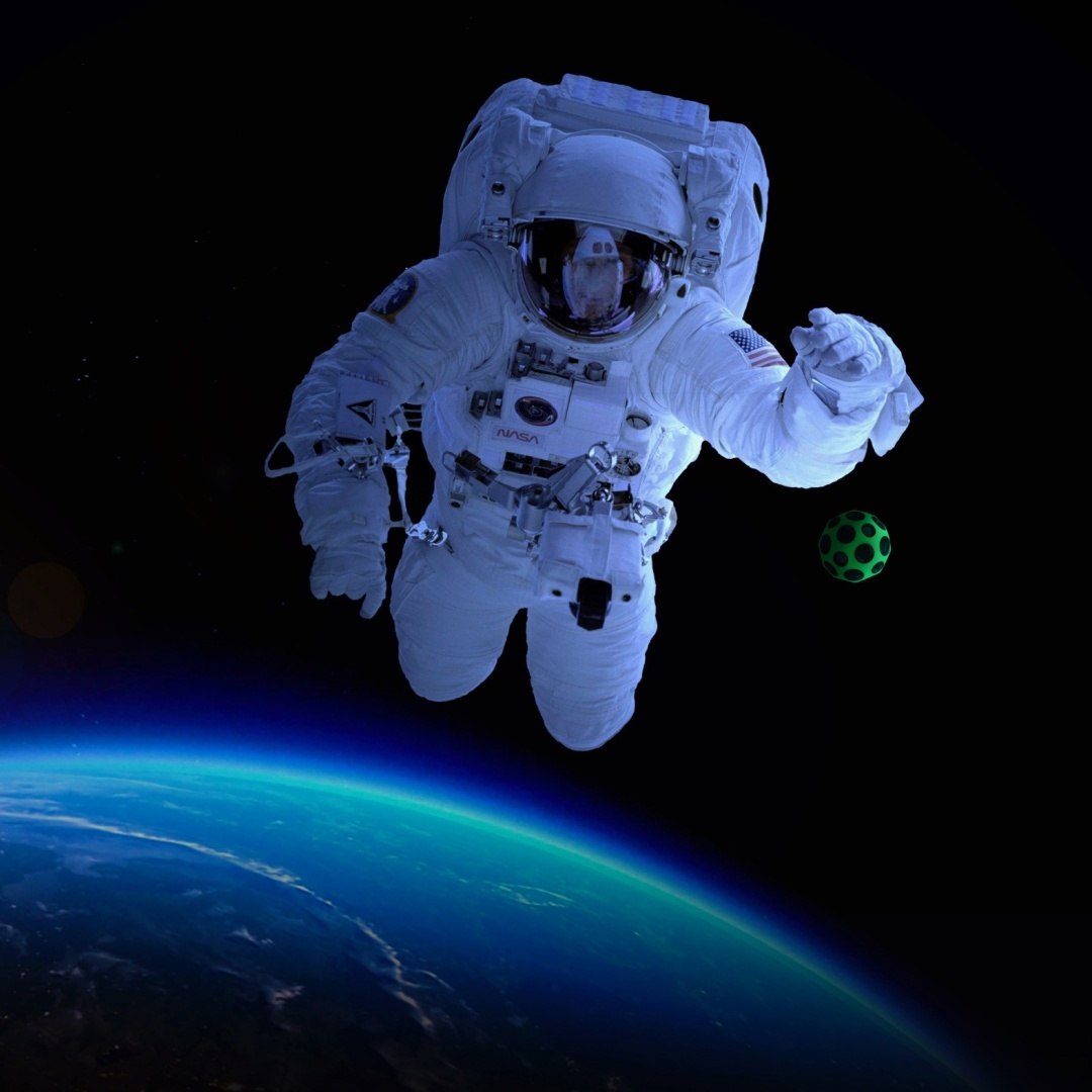 Astronauta unoszący się w kosmosie z piłeczką Waboba Moon Ball żółtą w tle Ziemia