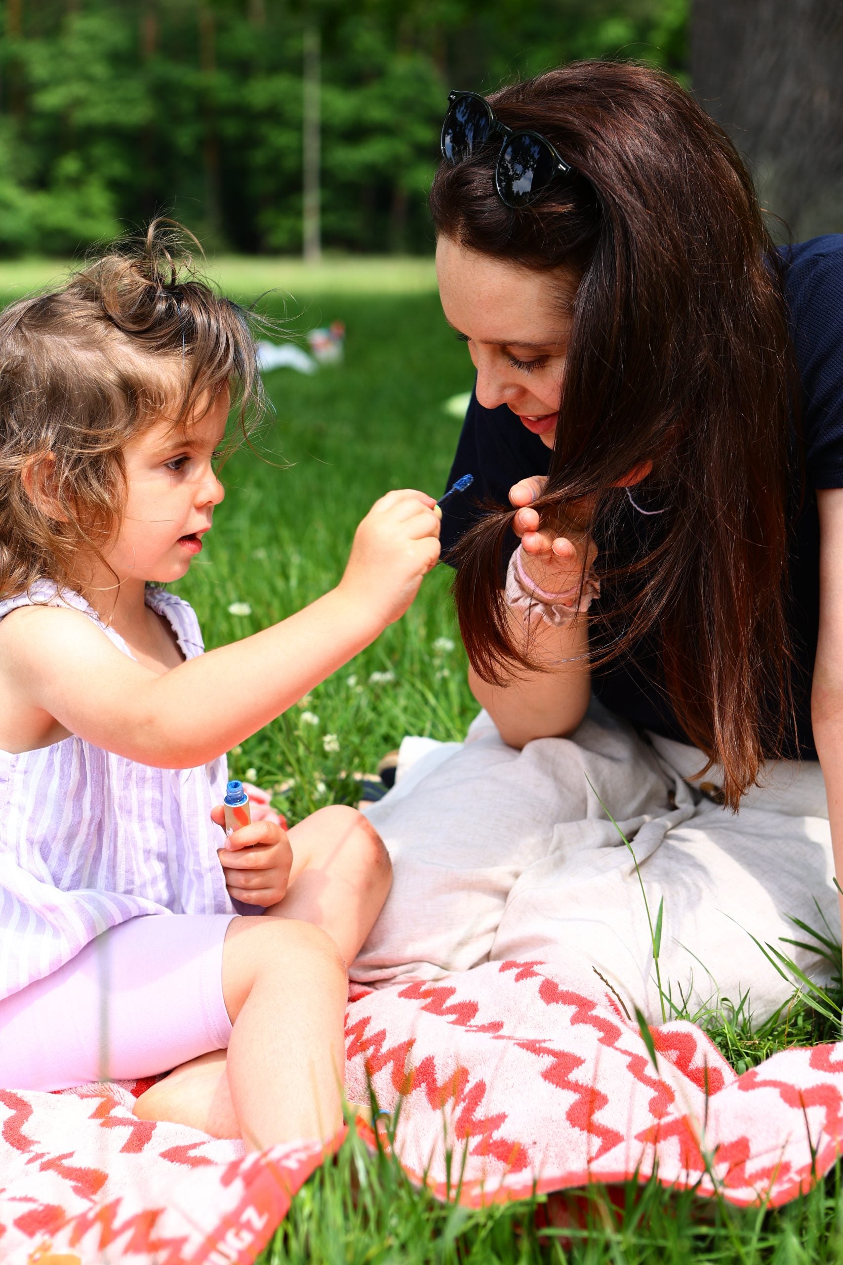 Exiba a embalagem da máscara de cabelo Yamann na grama enquanto uma mãe e seu filho brincam