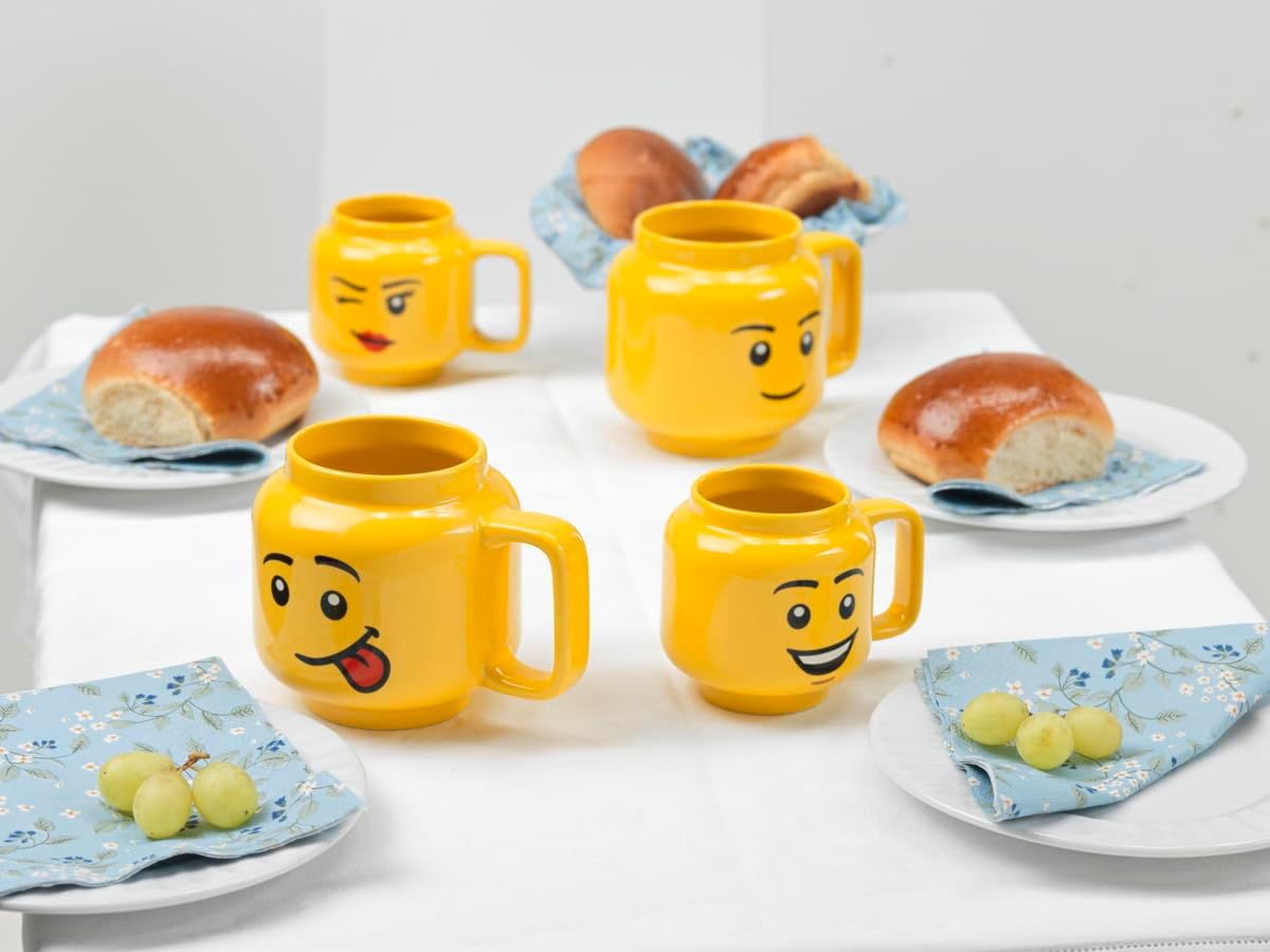 Kolorowe kubki LEGO głowa chłopiec z różnymi wyrazami twarzy na stole z pieczywem i winogronami