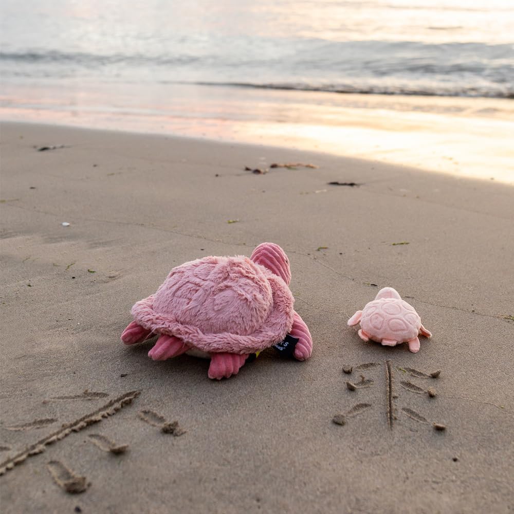 Pluszowy żółw mama i dziecko w różowym kolorze na plaży z widokiem na morze