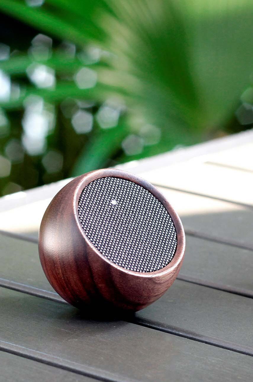 Głośnik bezprzewodowy orzech o okrągłym kształcie na zewnątrz na drewnianym stole