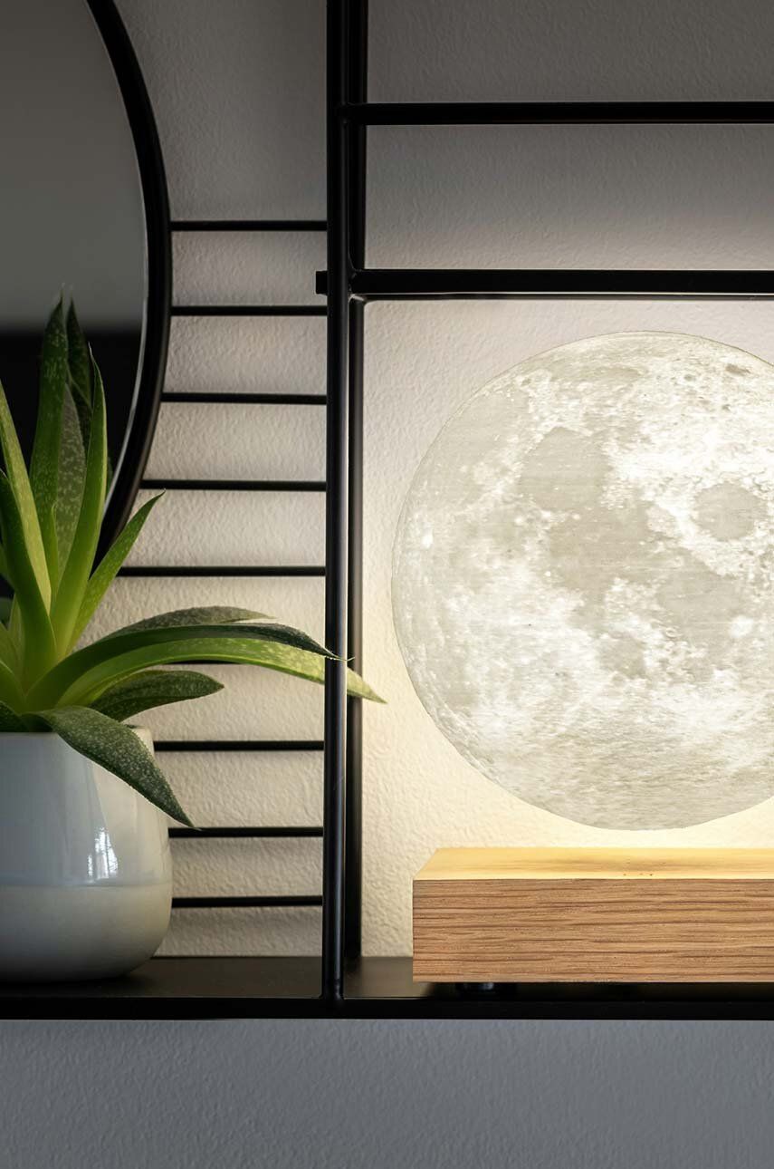 Inteligentna lampa księżycowa WABOBA AB przedstawiona na drewnianej podstawce na półce z rośliną obok