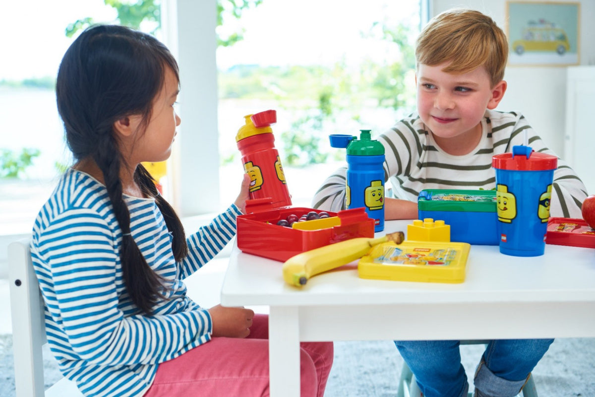 Dzieci bawiące się przy stole z kolorowymi bidonami LEGO dla dzieci i zabawkami