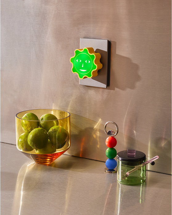 Lampka nocna dla dzieci Areaware w kształcie zielonego słońca zamontowana na ścianie w nowoczesnym wnętrzu