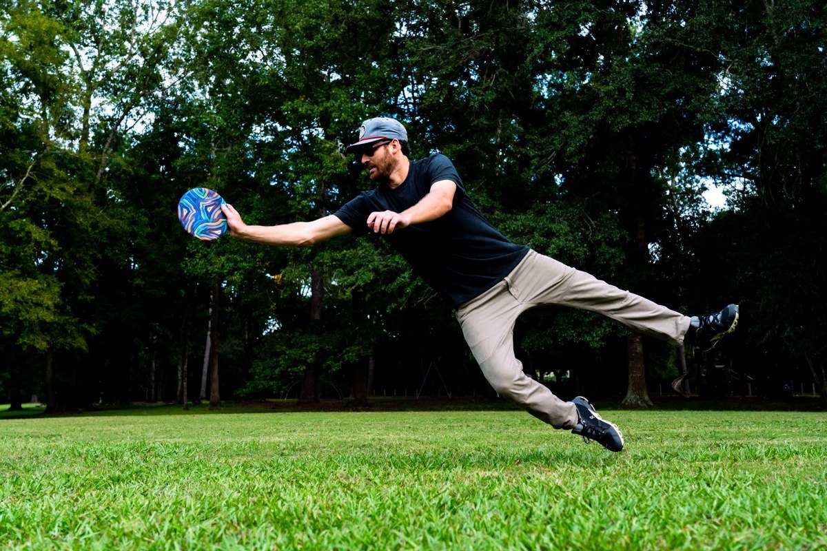 Mężczyzna w powietrzu chwytający frisbee Waboba Wingman Pro podczas gry w parku