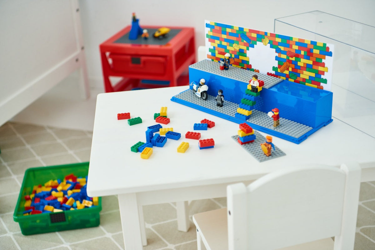Gablotka na LEGO z platformą na białym stoliku z kolorowymi klockami LEGO i minifigurkami