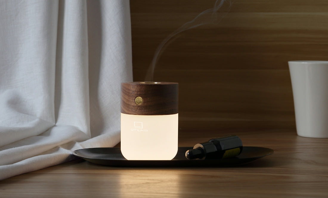 Elegancka inteligentna lampa z dyfuzorem o drewnianej górnej części na czarnej podstawce