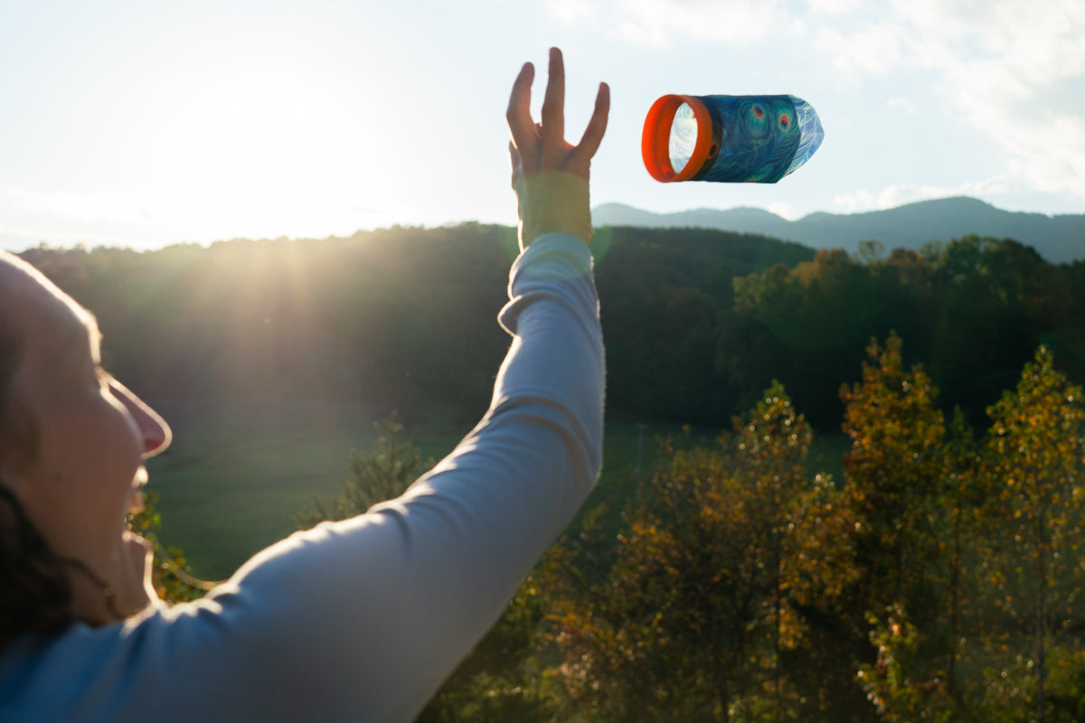 Osoba rzucająca rzutką Waboba Airlyft na zewnątrz na tle gór i lasu podczas zachodu słońca