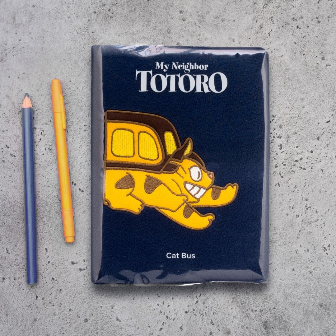 pluszowy notatnik kotobus z motywem Cat Bus z filmu Mój Sąsiad Totoro obok długopis i ołówek