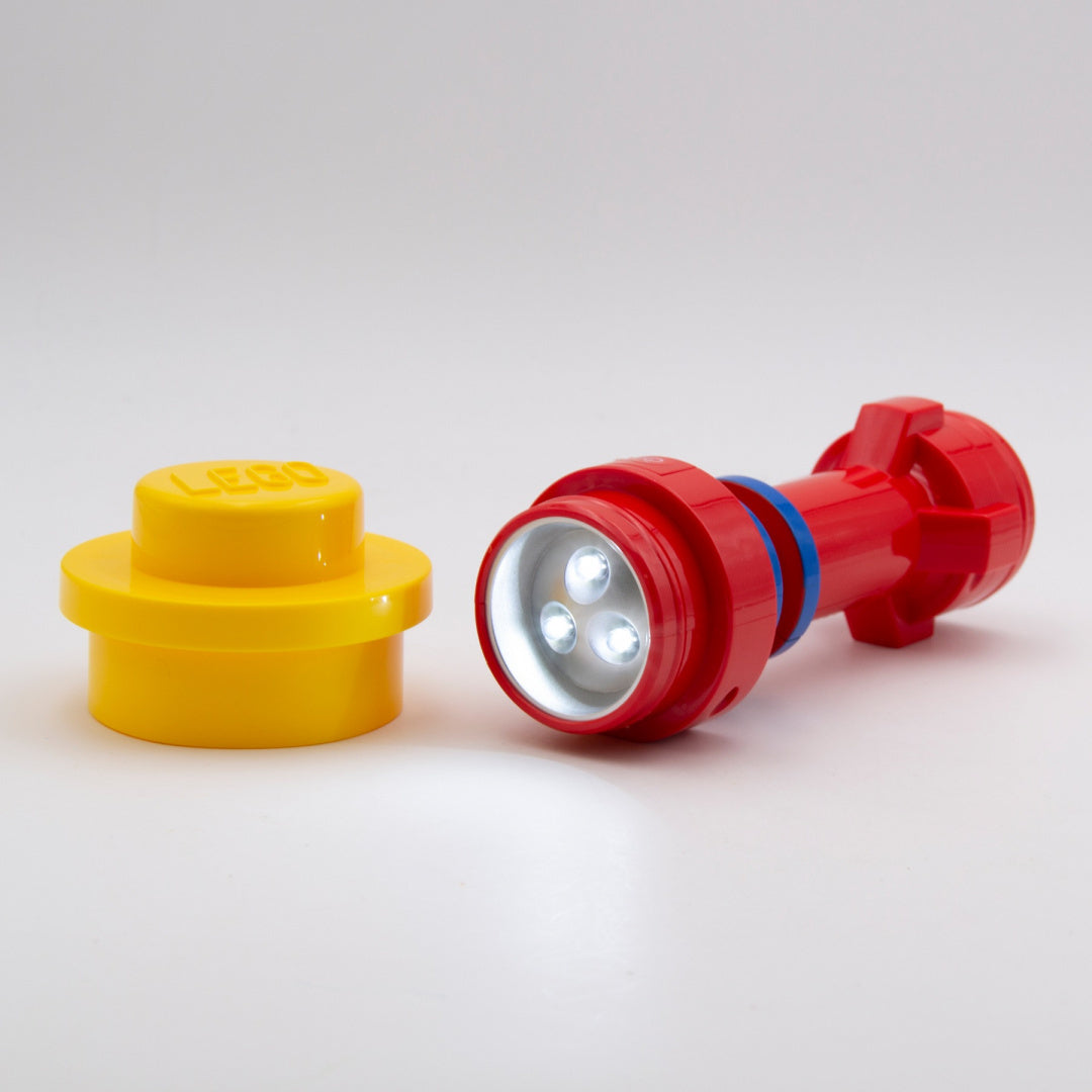 Czerwona latarka LEGO Classic czerwona obok żółtego klocka LEGO na białym tle