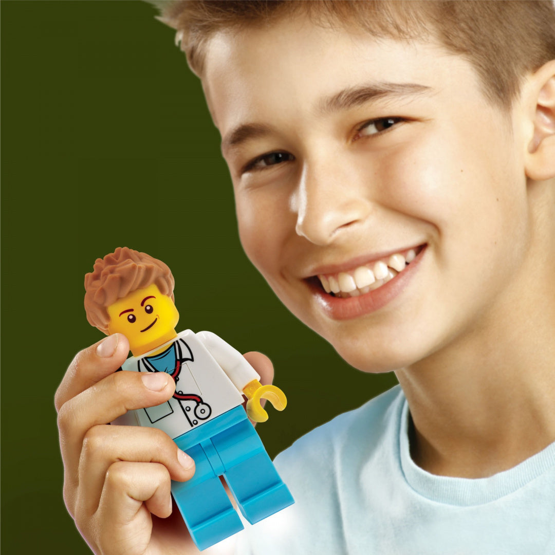 Chłopiec trzyma zabawkę latarka LEGO lekarz figurka doktora z kubraczką i stetoskopem