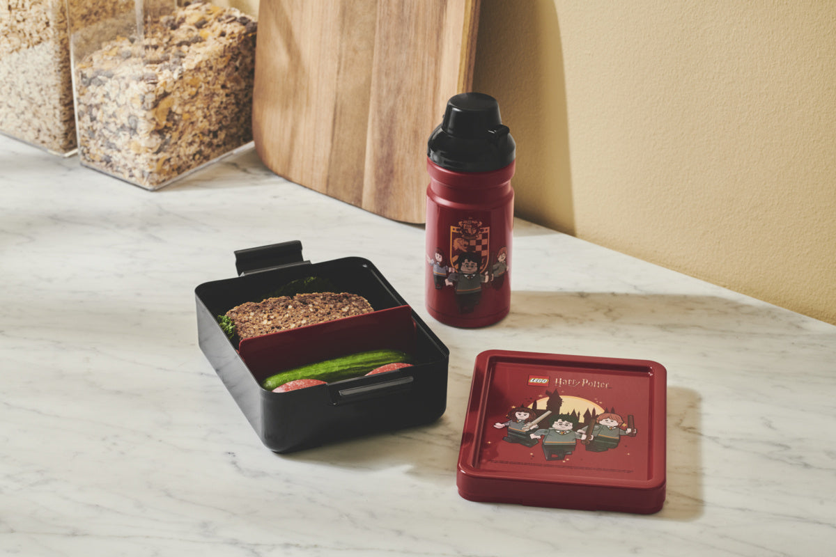 Lunchbox LEGO Harry Potter Gryffindor w kolorze bordowym z pojemnikiem na kanapki i bidonem na stoliku kuchennym