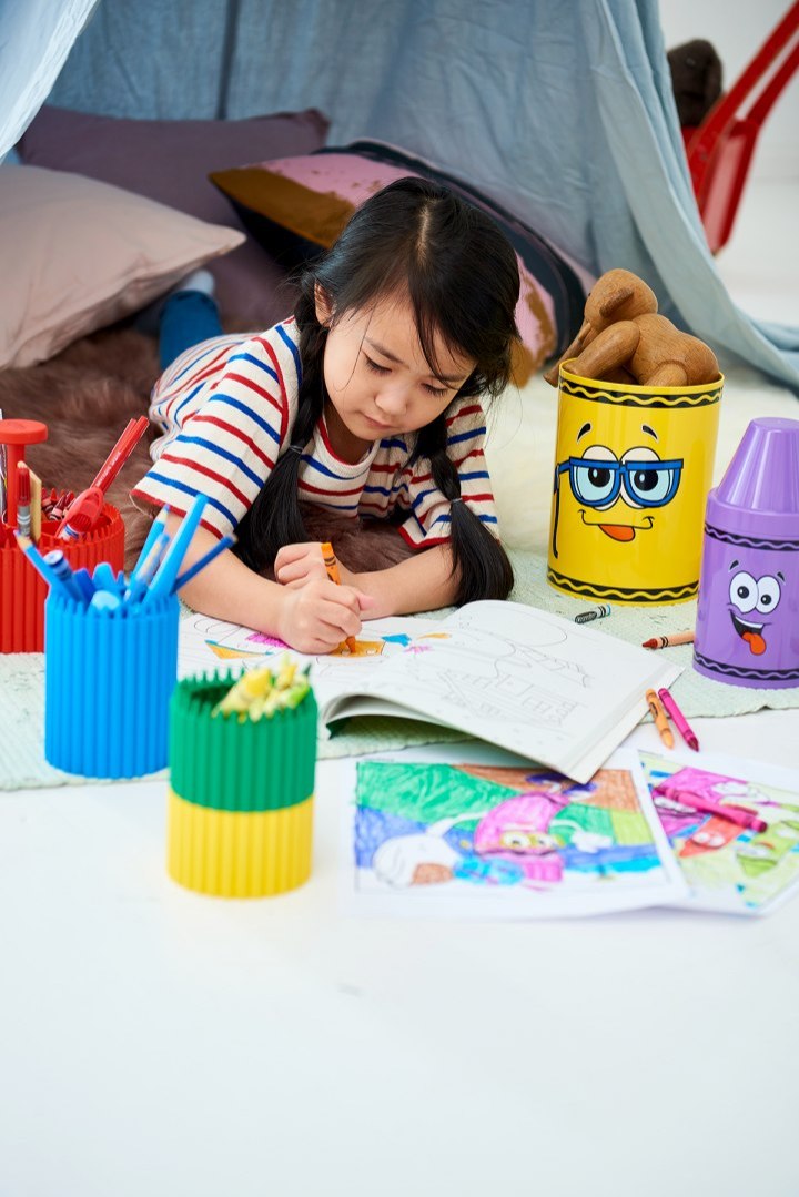 Mały pojemnik Crayola czerwony z kolorowymi kredkami na stole podczas rysowania dziecka