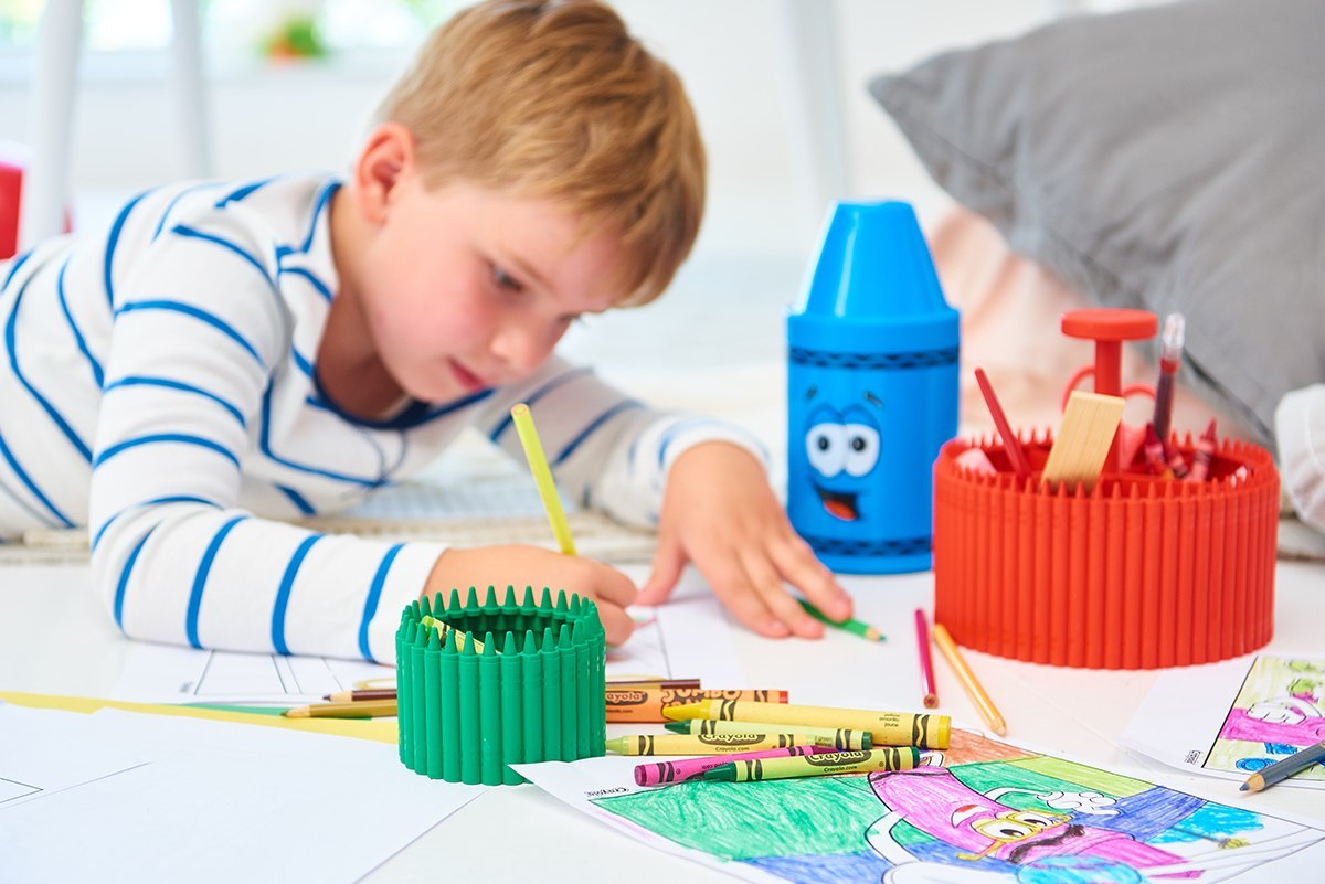 Dziecko rysujące z małym pojemnikiem Crayola czerwonym i innymi przyborami do kolorowania