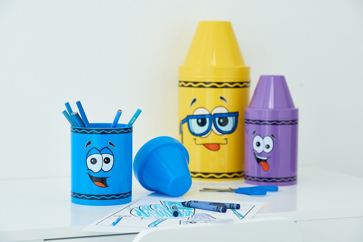 Pojemnik na kredki Crayola zielony nie jest na zdjęciu, lecz niebieski, żółty i fioletowy pojemnik z kolorowymi kredkami i rysunkami
