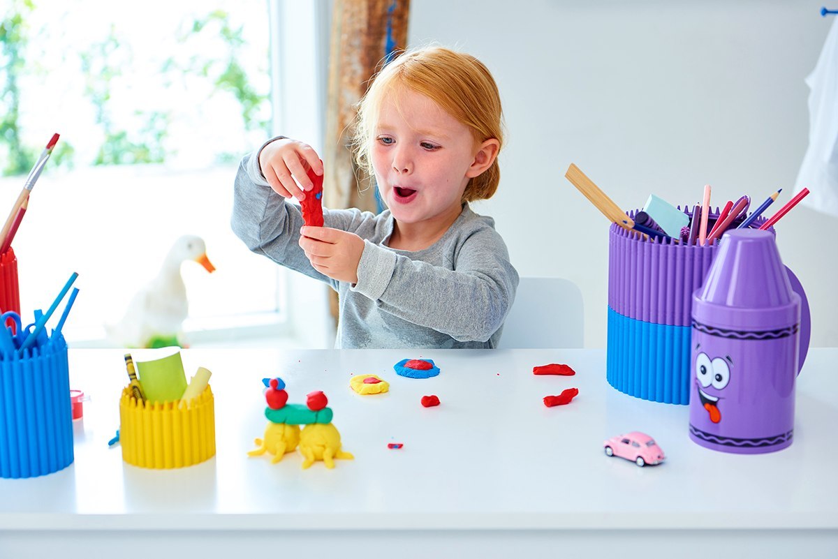 Dziecko bawiące się przy biurku z pojemnikiem na kredki Crayola zielony i innymi akcesoriami do rysowania
