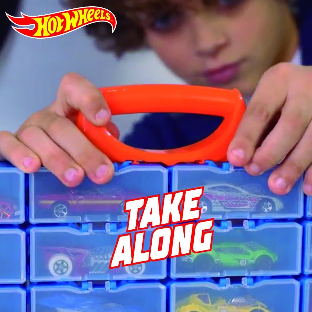 Dziecko trzyma modułowa walizka Hot Wheels z czerwonym uchwytem i samochodzikami w środku