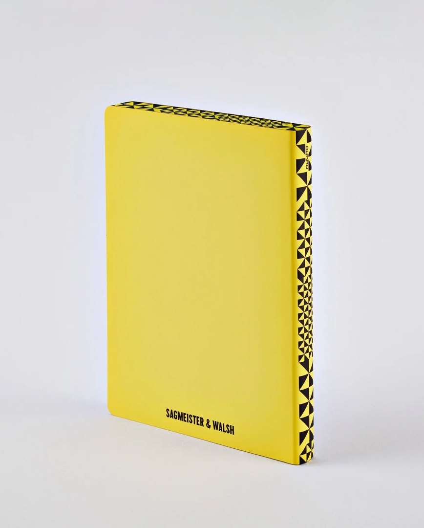 Żółty notatnik The Happy Book z geometrycznym wzorem na grzbiecie i logo Sagmeister & Walsh