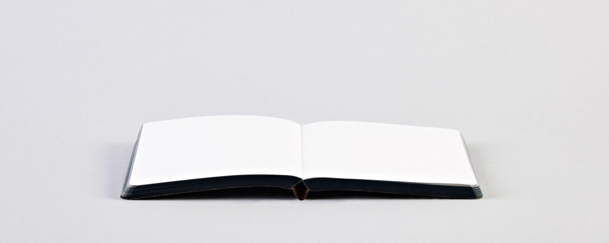 Otwarty notatnik graficzny BV JACOB COMPANY z pustymi białymi kartkami na szarym tle