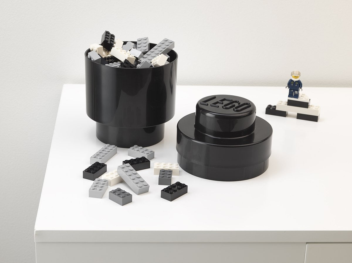 Czarny okrągły pojemnik LEGO czarny z klockami i przykrywką na białym blacie