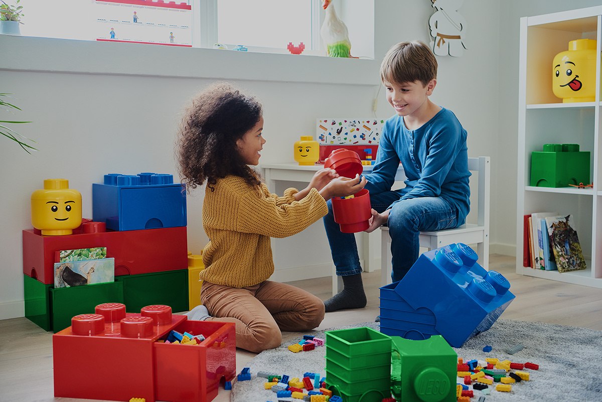 Dzieci bawiące się pojemnik klocek LEGO czerwony z kolorowymi klockami w pokoju zabaw