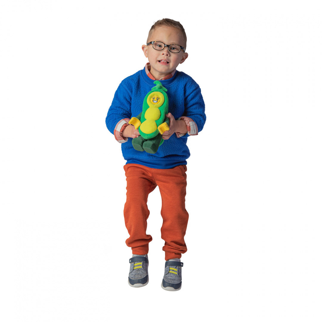 Dziecko trzymające pluszak LEGO Groszek w kształcie zielonego groszku z uśmiechniętą twarzą