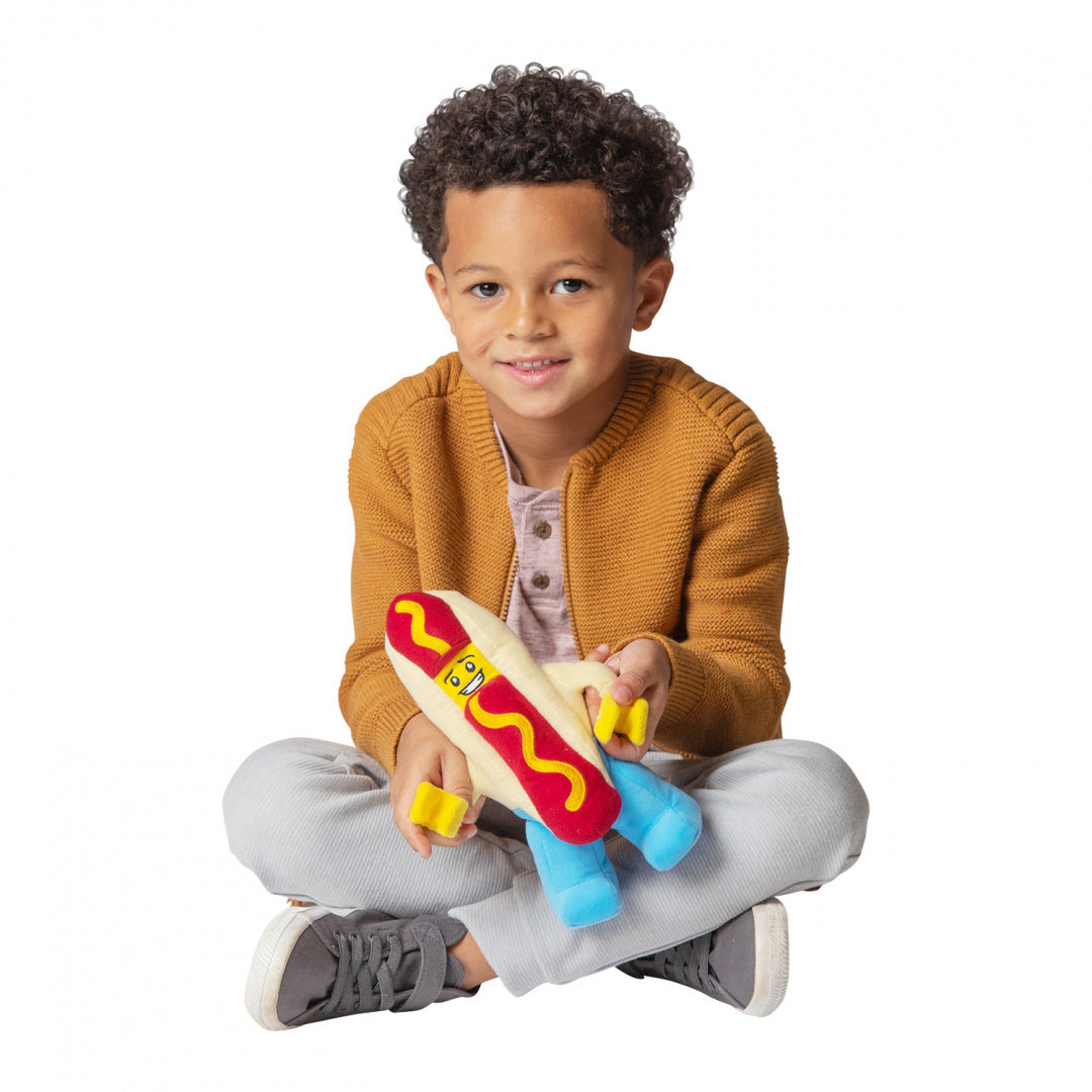 Dziecko bawi się pluszakiem LEGO hot dog z żółtym i niebieskim nadrukiem