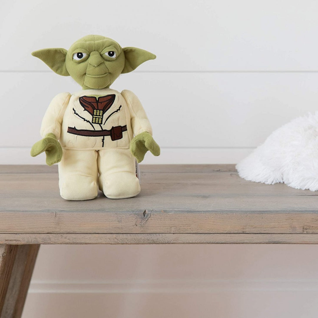 Pluszak Yoda LEGO Star Wars siedzący na drewnianym stole z białym tłem