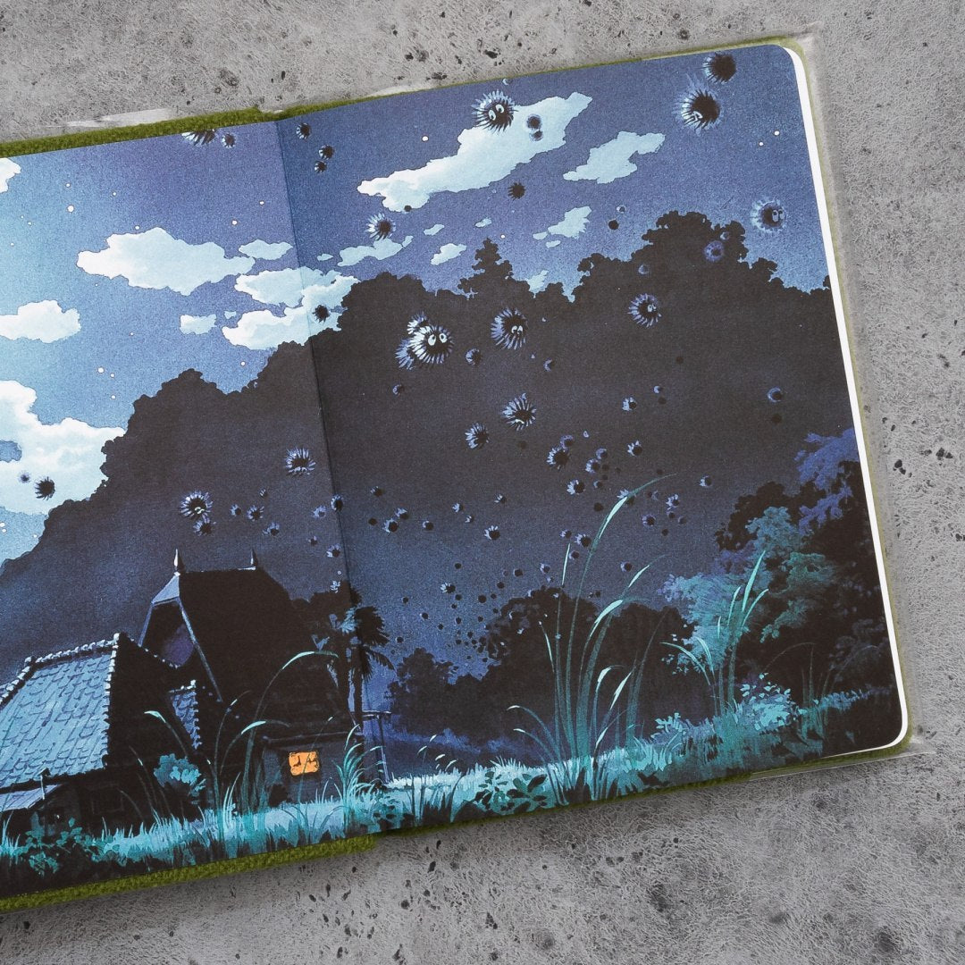 Pluszowy notatnik Totoro z ilustracją nocnego krajobrazu i latającymi pyłkami na otwartej stronie