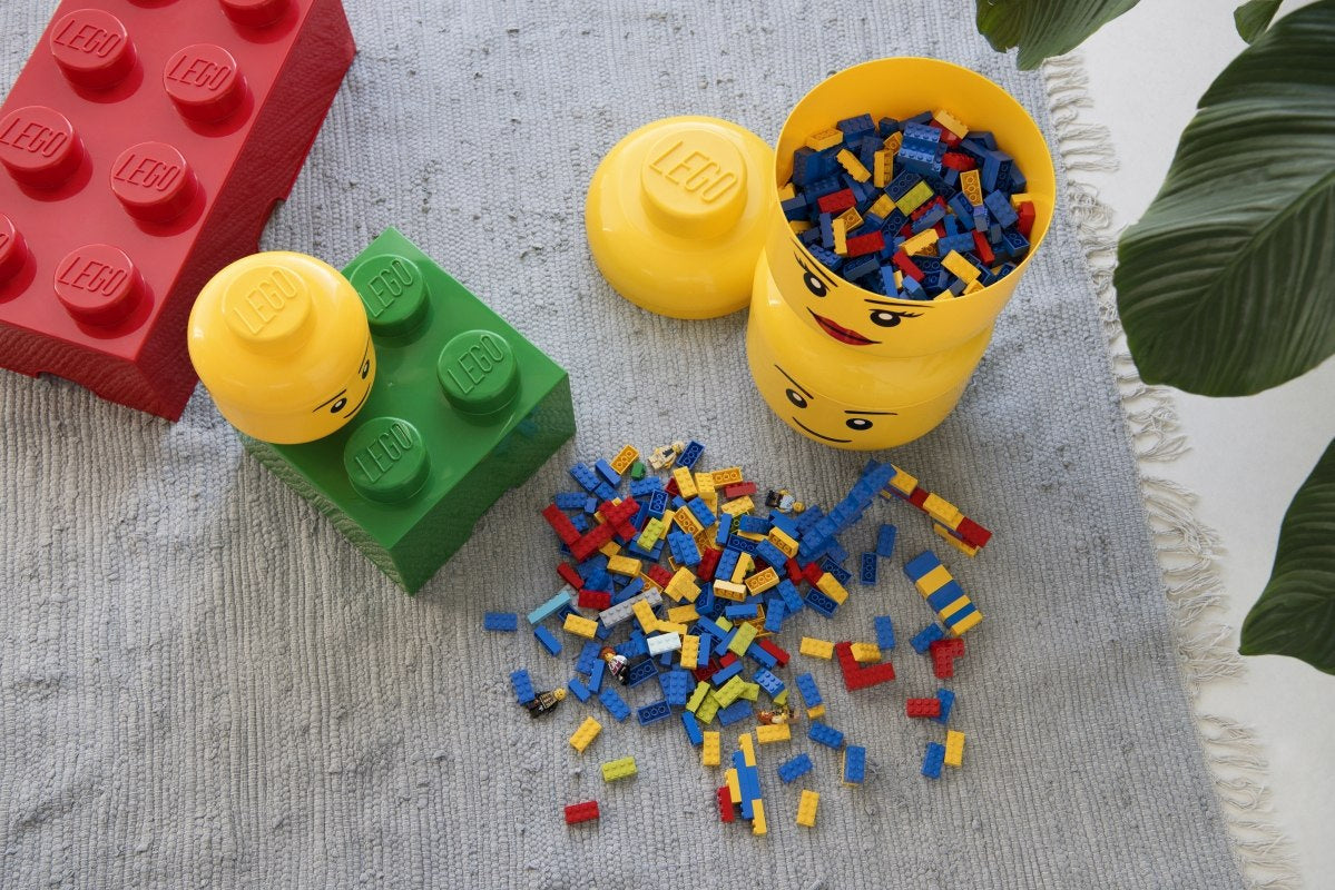 Pojemnik LEGO duża głowa chłopiec żółty z kolorowymi klockami i dużymi klockami LEGO na szarym dywanie