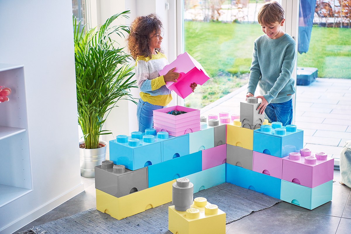 Dzieci bawią się szarym pojemnikiem LEGO Brick szary i kolorowymi pojemnikami klocków w domu