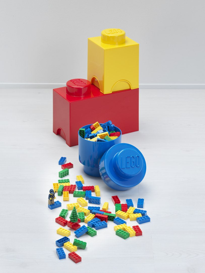 Pojemnik LEGO czerwony w kształcie klocka z rozsypanymi kolorowymi klockami LEGO obok