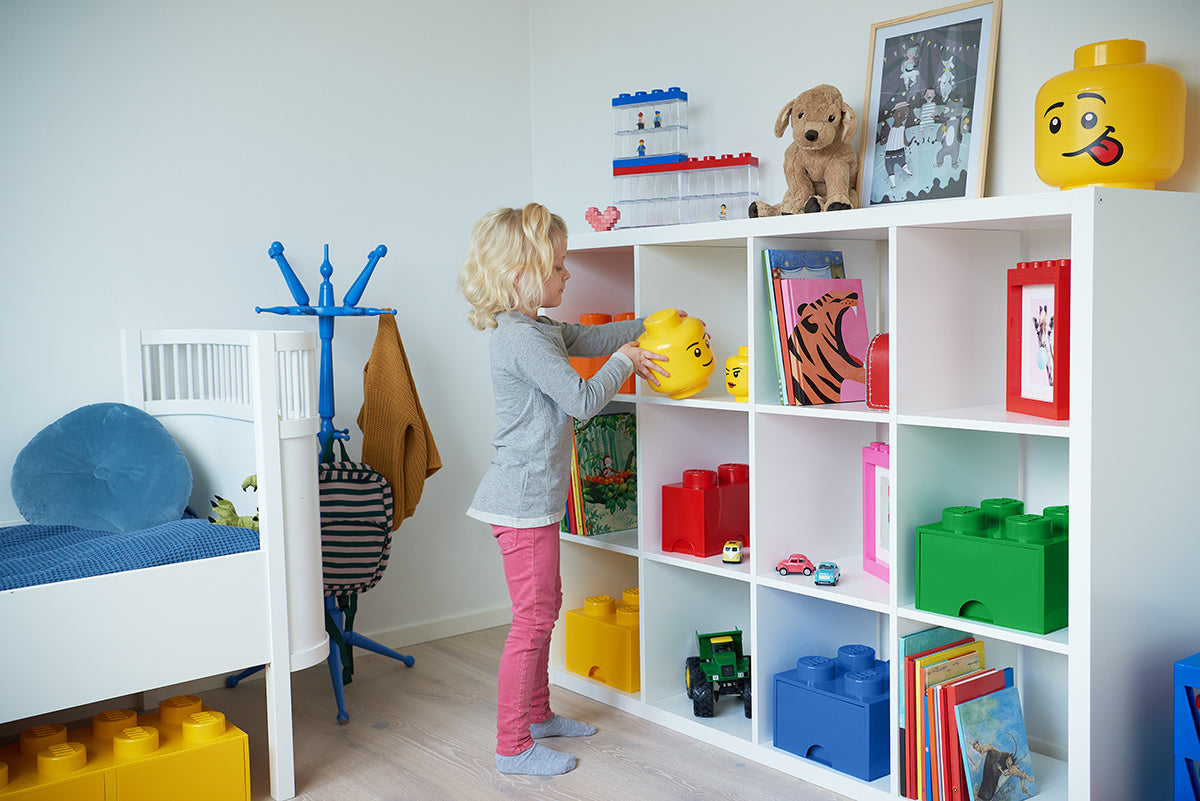 Dziecko sięgające po pojemnik LEGO Brick 8 żółty na półce w pokoju dziecięcym z zabawkami