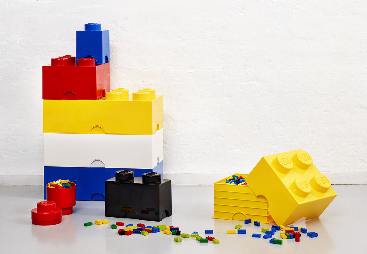 pojemnik LEGO Brick 8 żółty w kształcie klocka z kolorowymi małymi klockami na podłodze