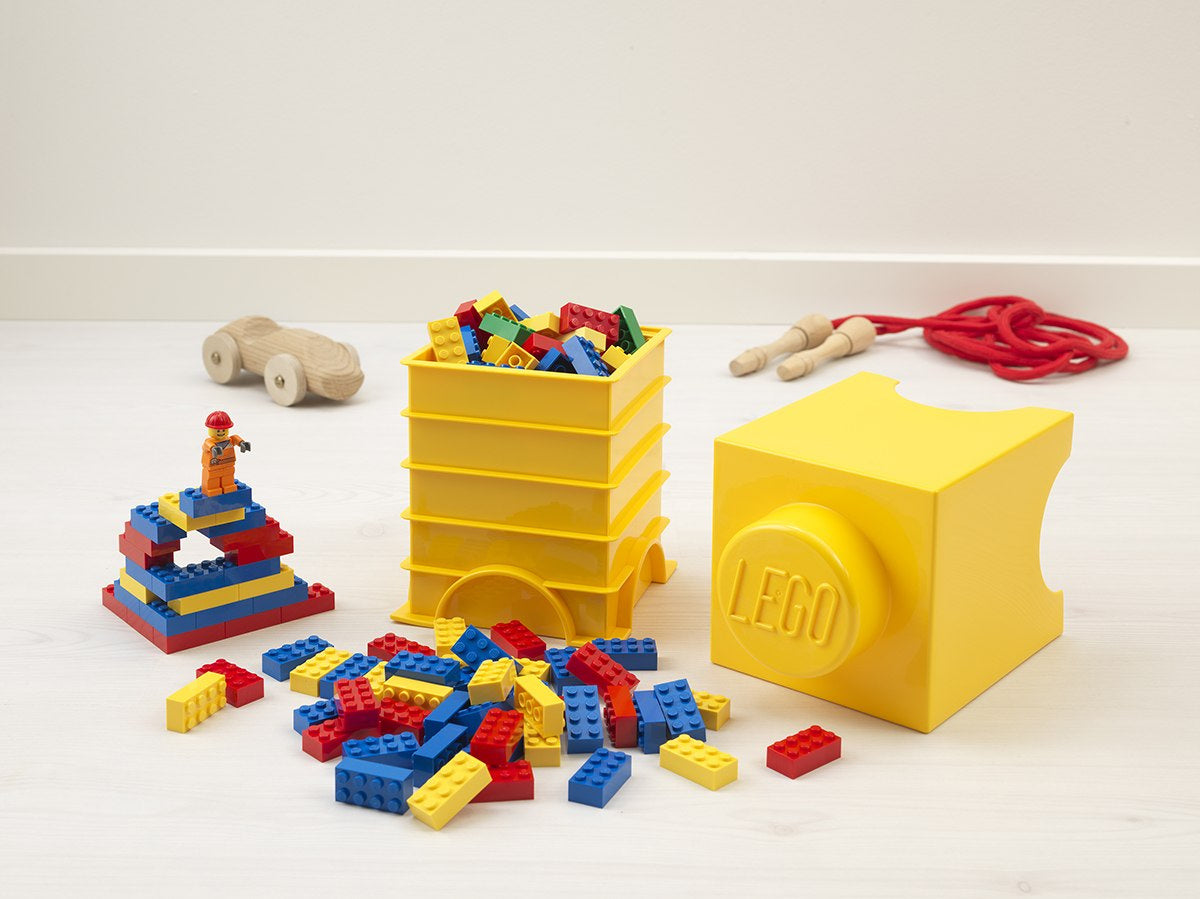 Żółty pojemnik LEGO klocek żółty z kolorowymi klockami LEGO i układaną zabawką na podłodze
