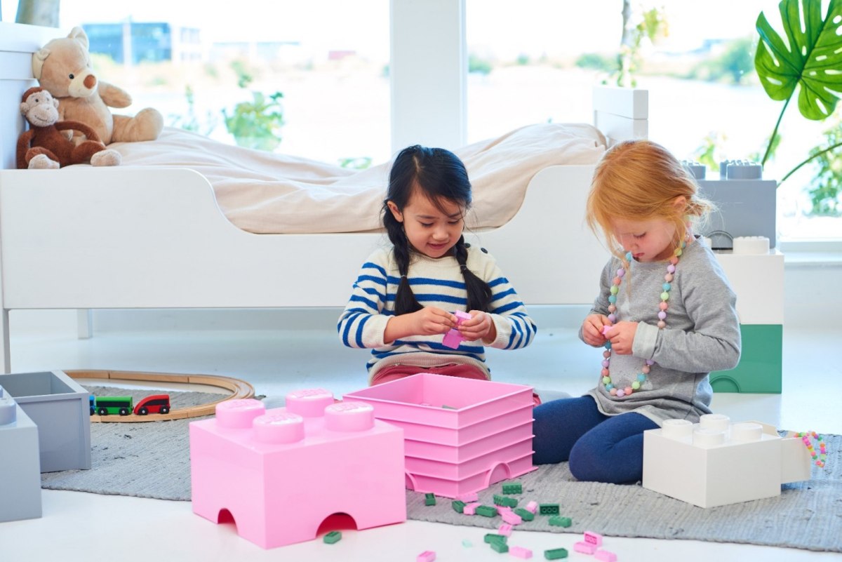 Dzieci bawiące się pojemnikiem LEGO Brick 4 jasnoróżowy w pokoju dziecięcym z zabawkami