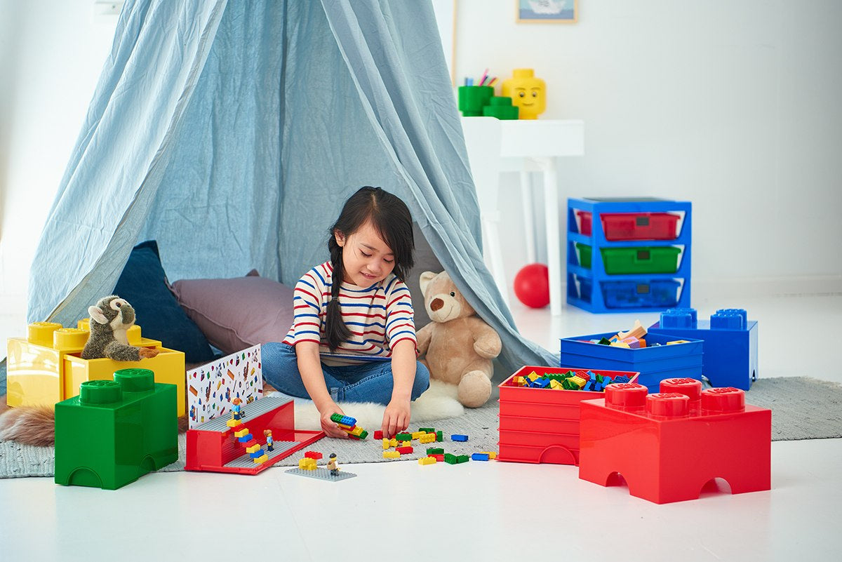 Dziecko bawiące się klockami LEGO z pojemnikiem LEGO Brick 4 czerwony w pokoju zabaw