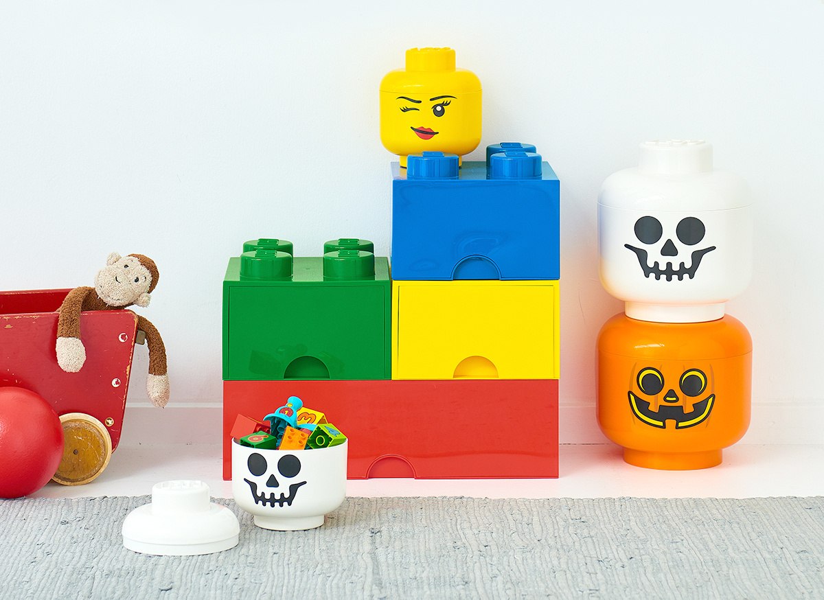 Pojemnik LEGO głowa dziewczynka z żółtą twarzą wśród kolorowych klocków i pojemników na klocki