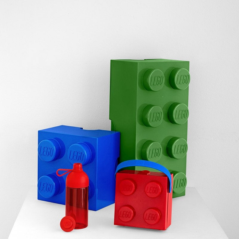 Butelka LEGO 500 ml czerwona z nakrętką obok dużych klocków LEGO w kolorze niebieskim i zielonym