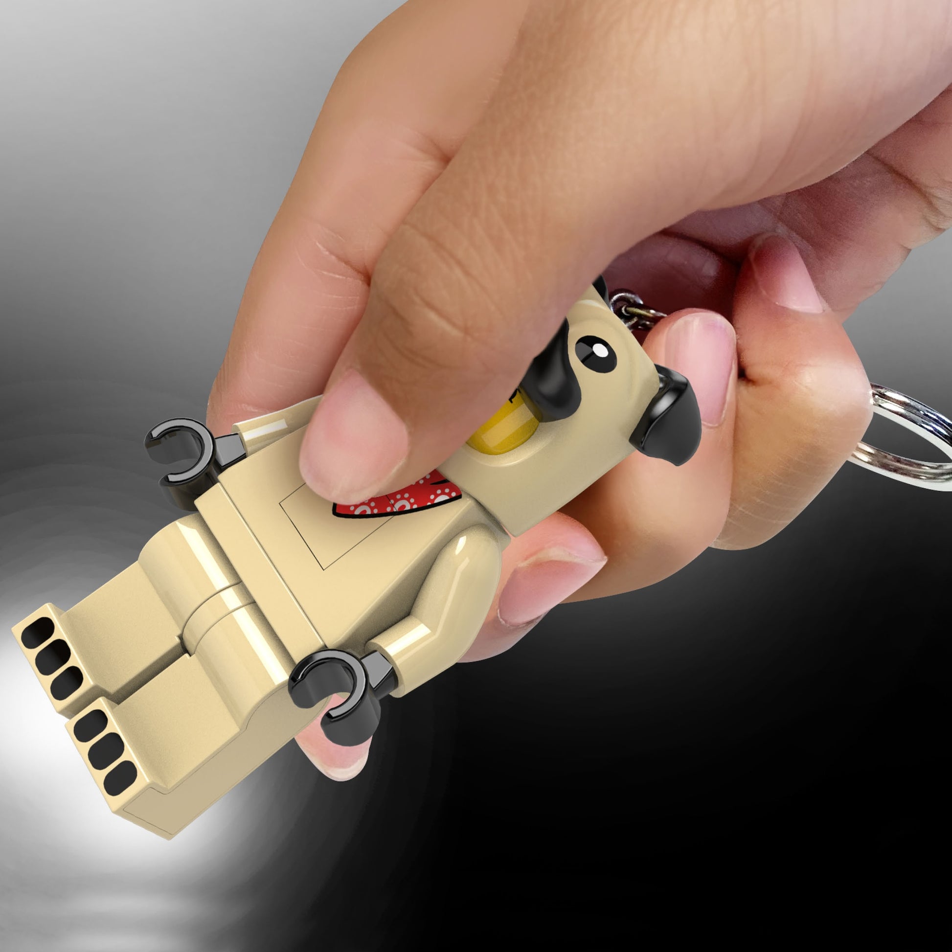 Brelok z latarką LEGO Mops trzymany w dłoni z kluczem, jasno oświetlający tło