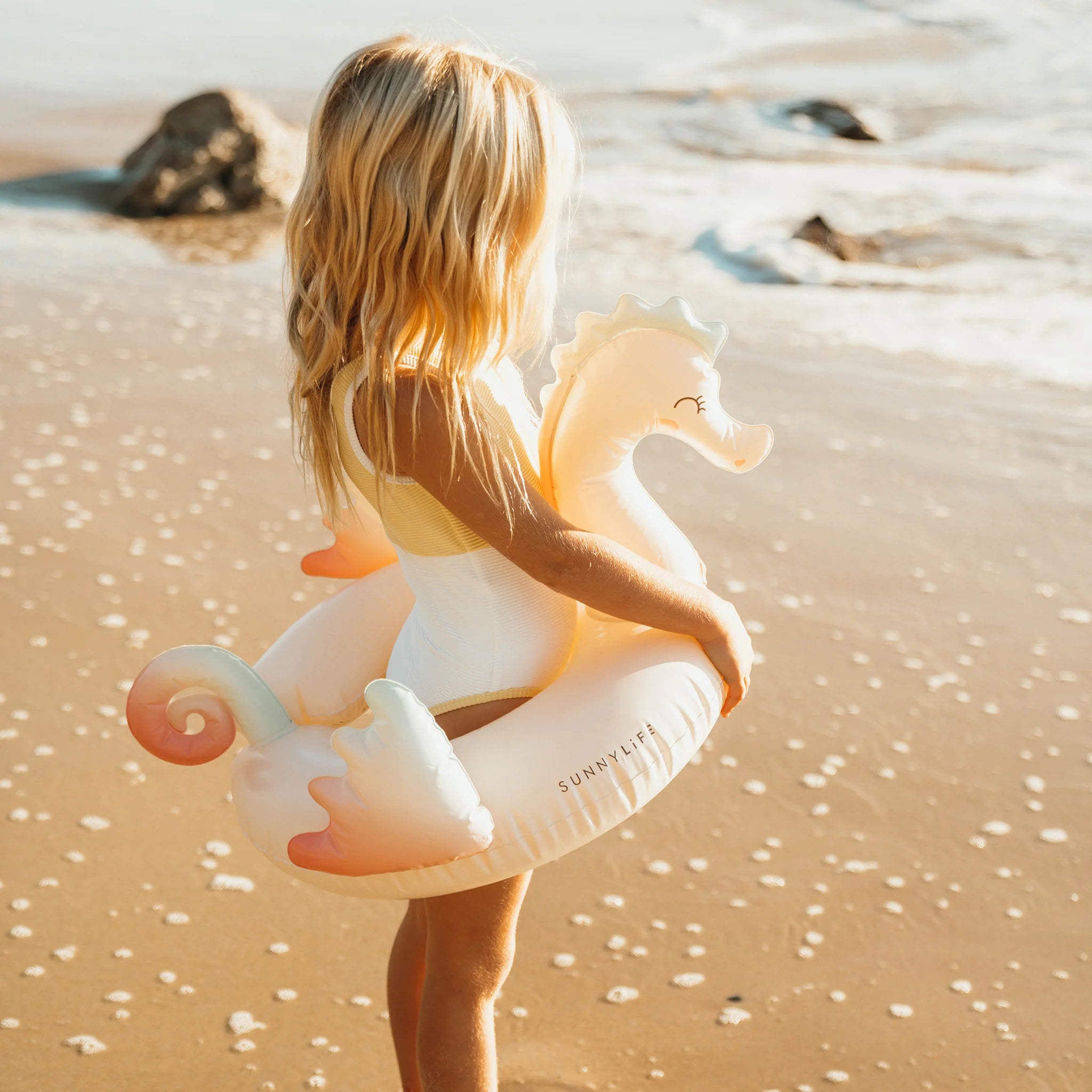 Dziewczynka na plaży z kołem do pływania dla dzieci syrenka marki Sunny Life