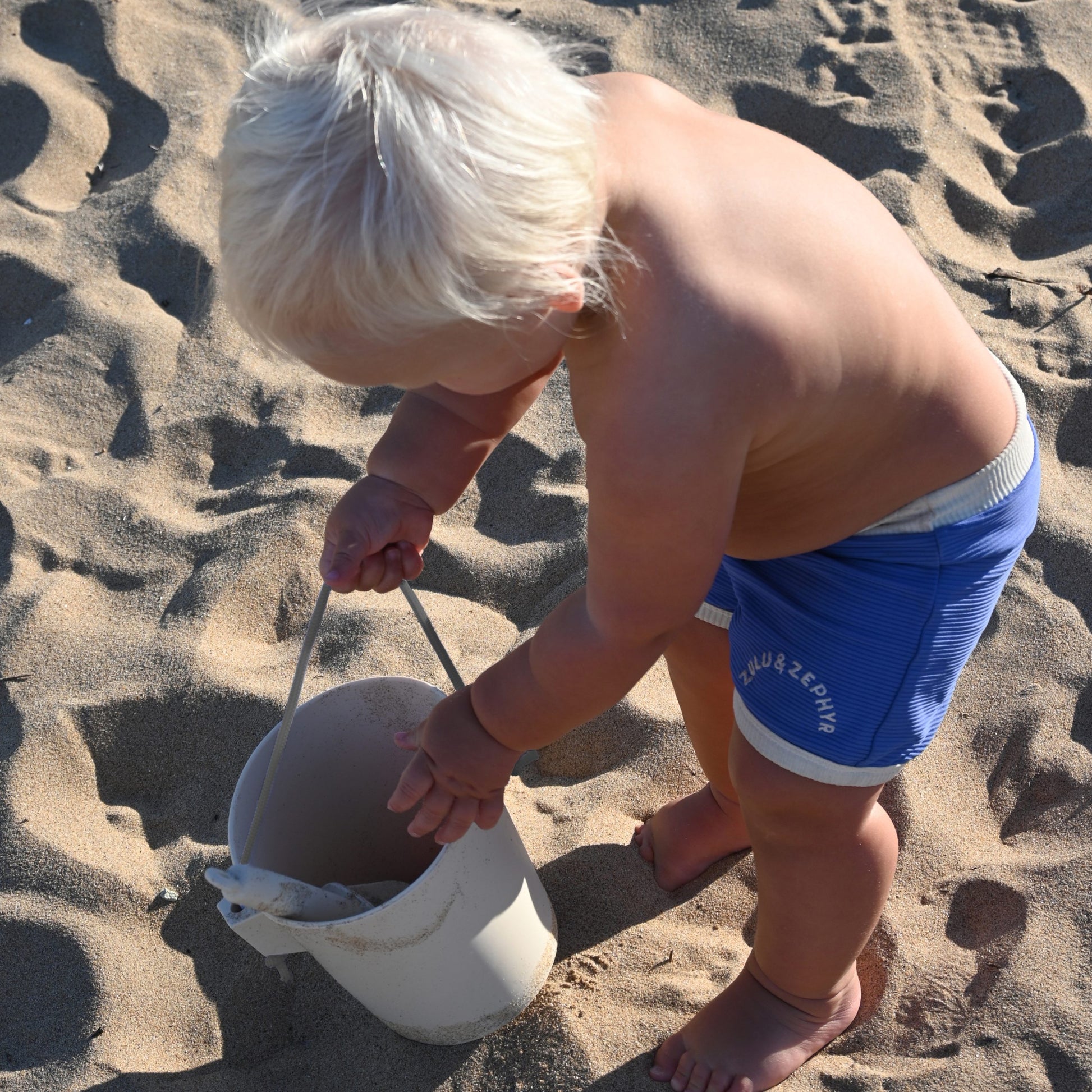 Dziecko bawiące się na plaży z silikonowe wiaderko dla dzieci marki Sunny Life