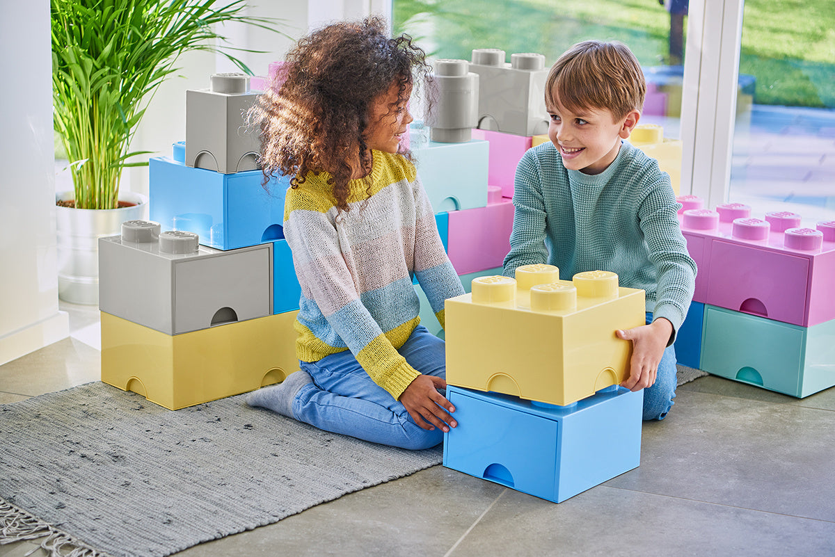 Dzieci bawiące się szufladą LEGO Brick 4 jasnoniebieska oraz innymi kolorowymi pojemnikami na klocki