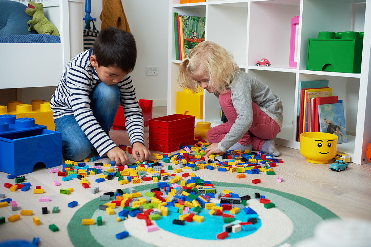 Dzieci bawiące się klockami LEGO na podłodze z widoczną zieloną szufladą LEGO Brick 4