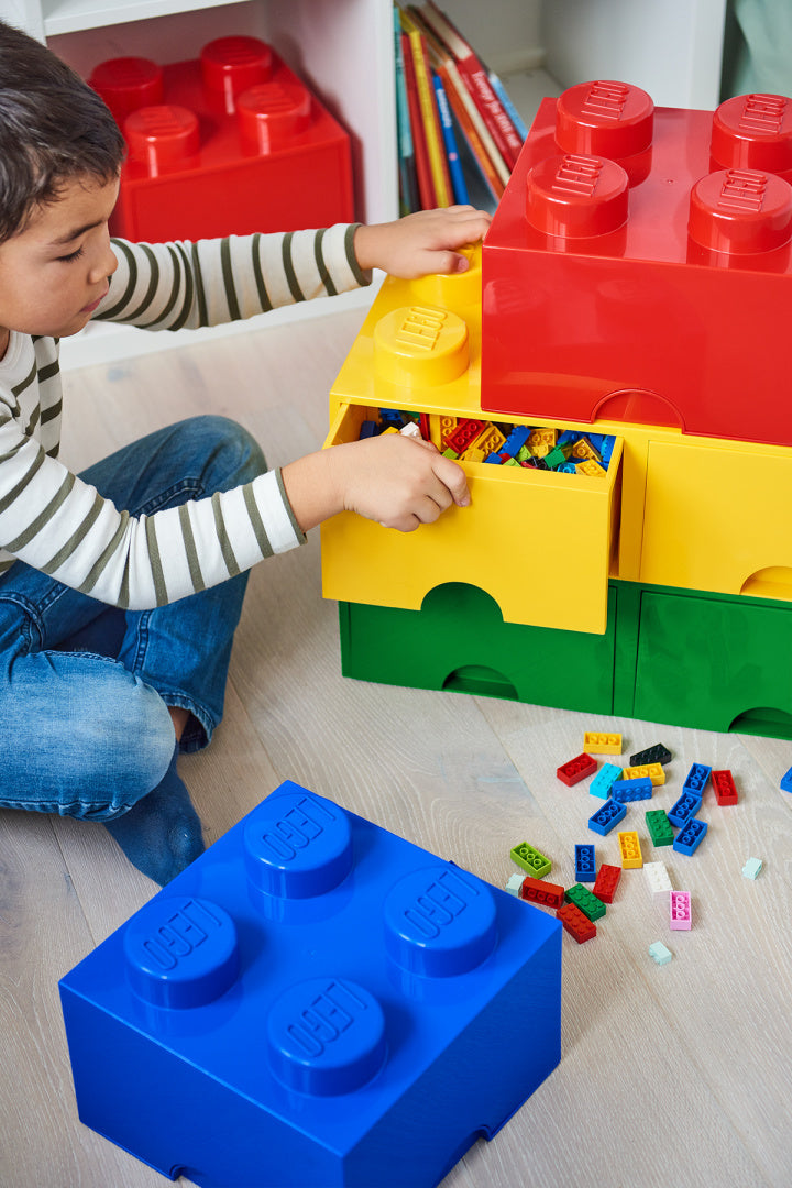 Dziecko bawiące się szufladą LEGO Brick 8 żółtą w kształcie dużej cegiełki z kolorowymi klockami