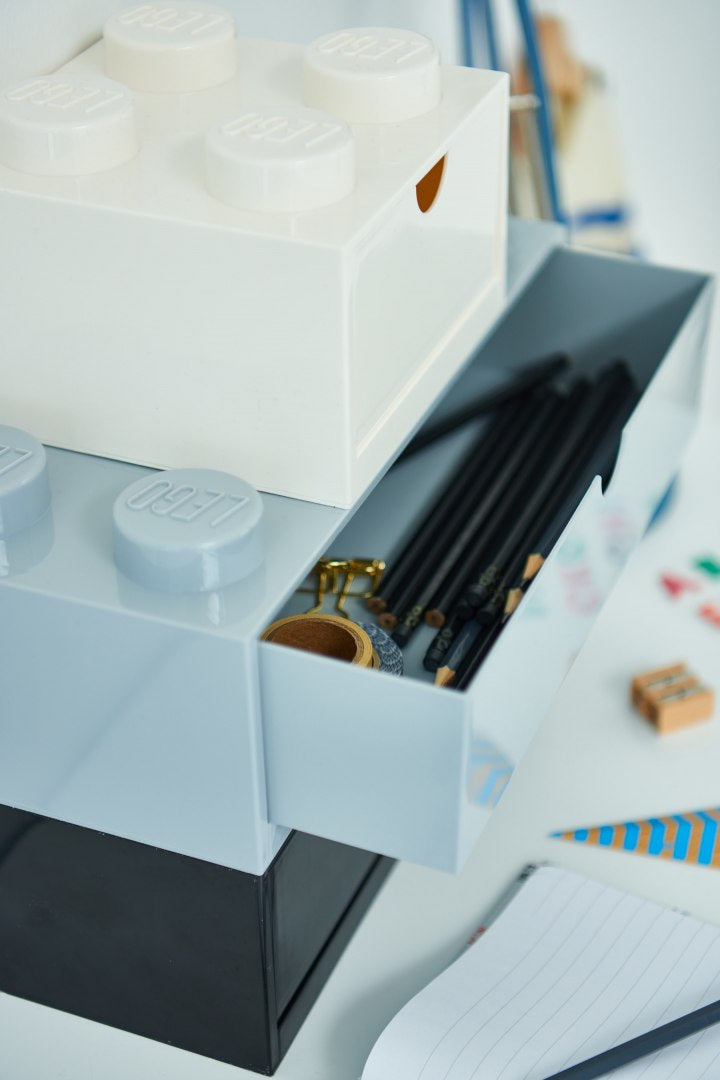 biała szufladka LEGO na biurko w kształcie klocka z otwartą szufladą na czarne długopisy