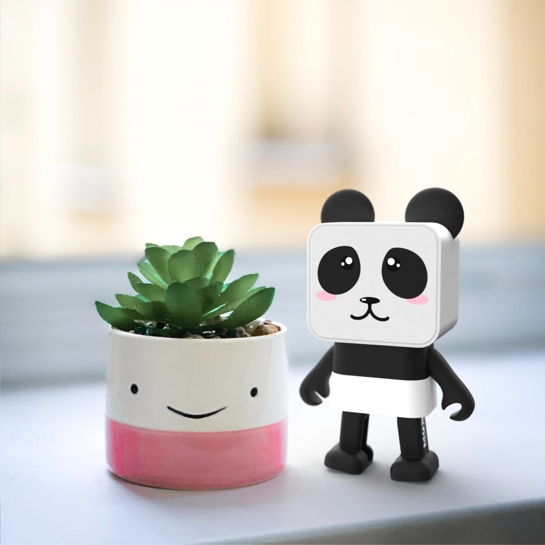 Tańczący głośnik bezprzewodowy panda obok doniczki z zielonym sukulentem na białym stole