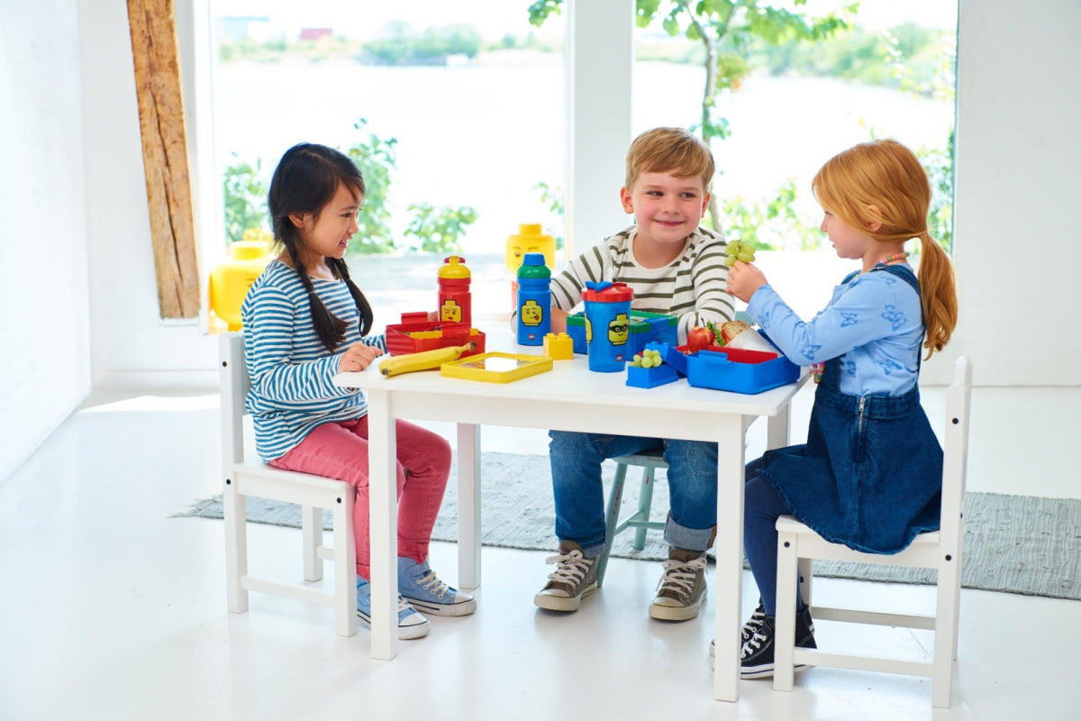 Lunchbox LEGO dla dziewczynki na stole podczas zabawy dzieci w jasnym pokoju