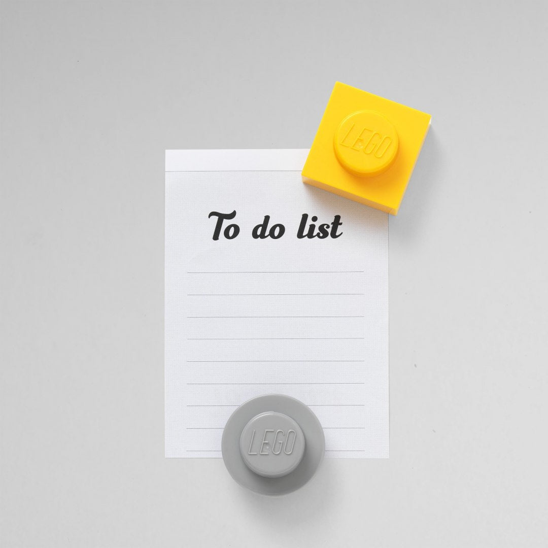 Szare magnesy LEGO szare w kształcie klocków trzymające karteczkę To do list na szarej powierzchni